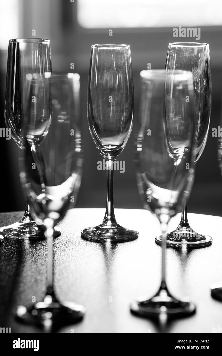 A black and white view of a group of champagne glasses arranged on a table. Stock Photo