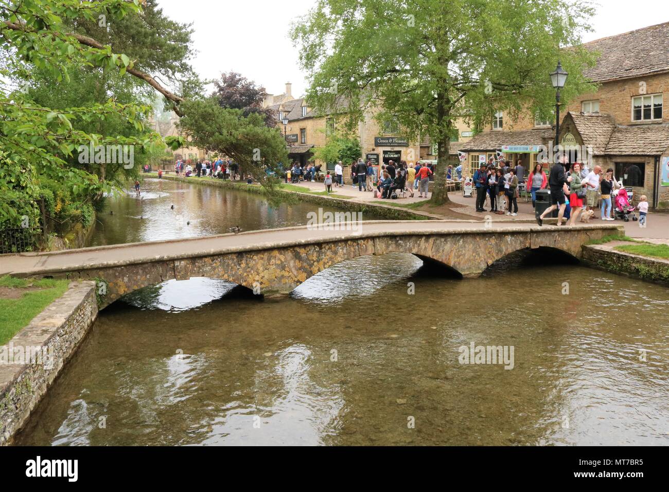 People enjoying the May Bank Holiday at Bourton on the Water, Gloucestershire, UK within the Cotswolds Area of Outstanding Natural Beauty Stock Photo