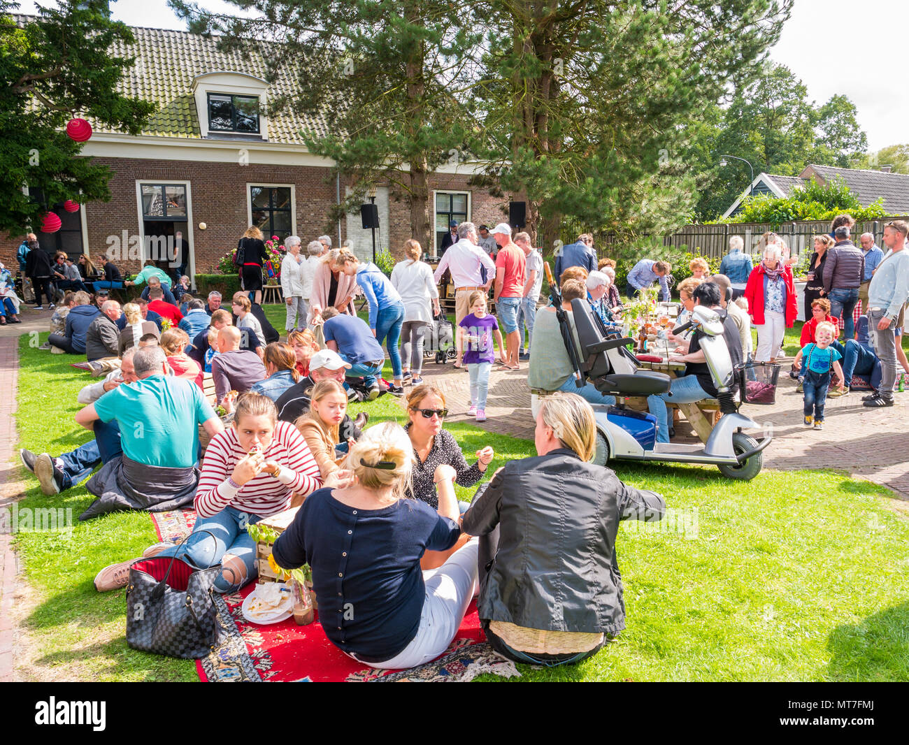People enjoying snacks and drinks on street food festival in garden of old orphanage in historic town of Bolsward, Friesland, Netherlands Stock Photo