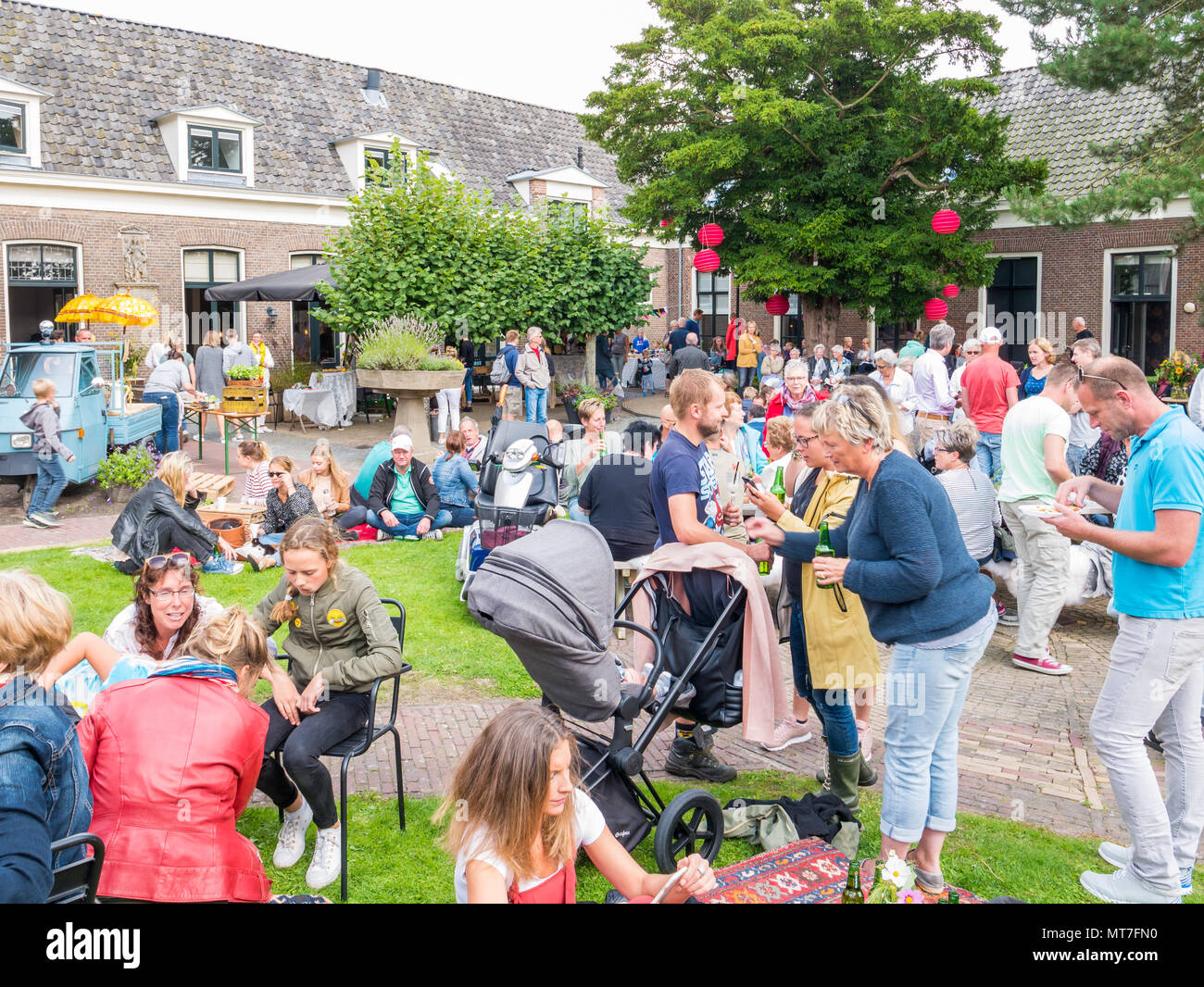 People enjoying snacks and drinks on street food festival in garden of old orphanage in historic town of Bolsward, Friesland, Netherlands Stock Photo
