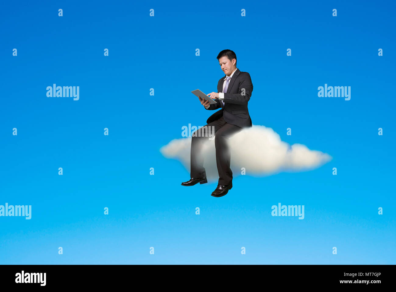 Businessman using digital tablet and sitting on cloud in sky background. Stock Photo