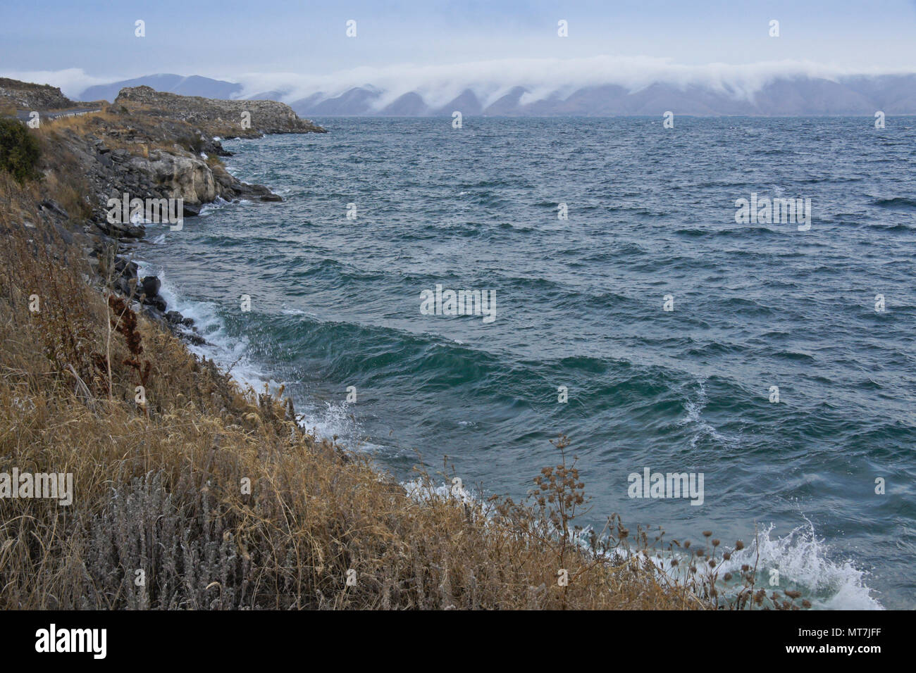 Clouds cascade down the hills surrounding Lake Sevan in Armenia on a very windy day in autumn Stock Photo