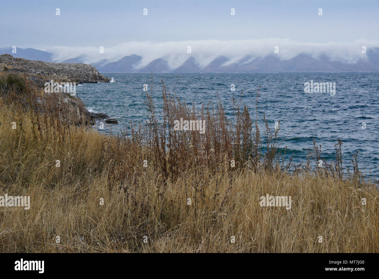 Clouds cascade down the hills surrounding Lake Sevan in Armenia on a very windy day in autumn Stock Photo
