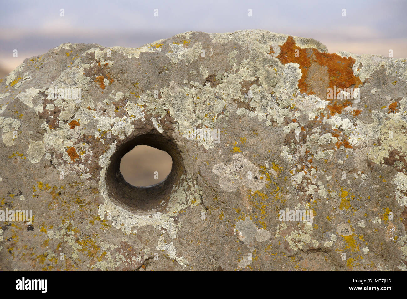 Lichen-encrusted rock with hole bored in it, Karahunj (Carahunge) Observatory near the town of Sisian, Armenia Stock Photo