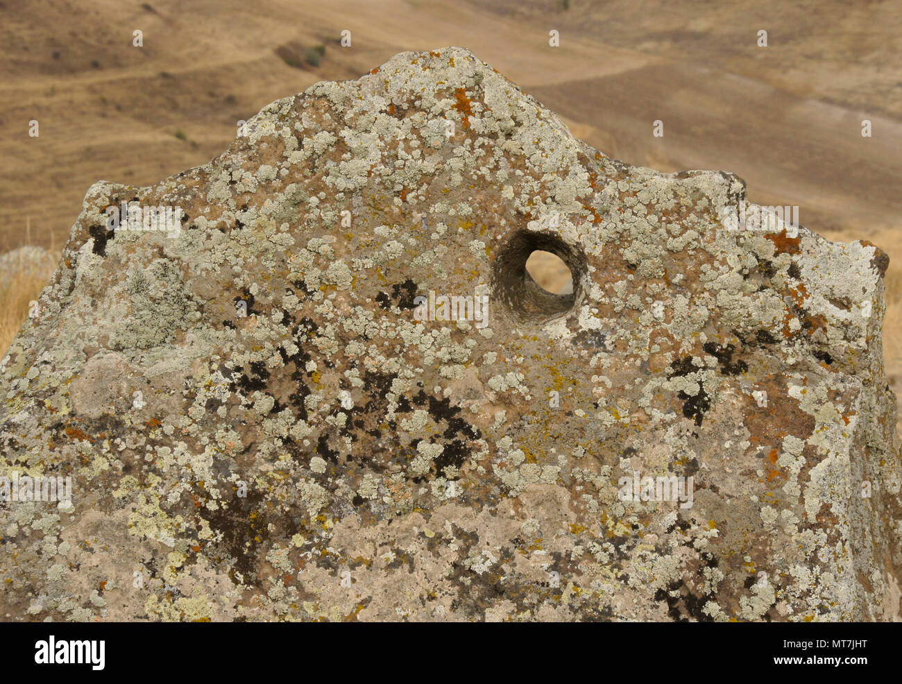Lichen-encrusted rock with hole bored in it, Karahunj (Carahunge) Observatory near the town of Sisian, Armenia Stock Photo