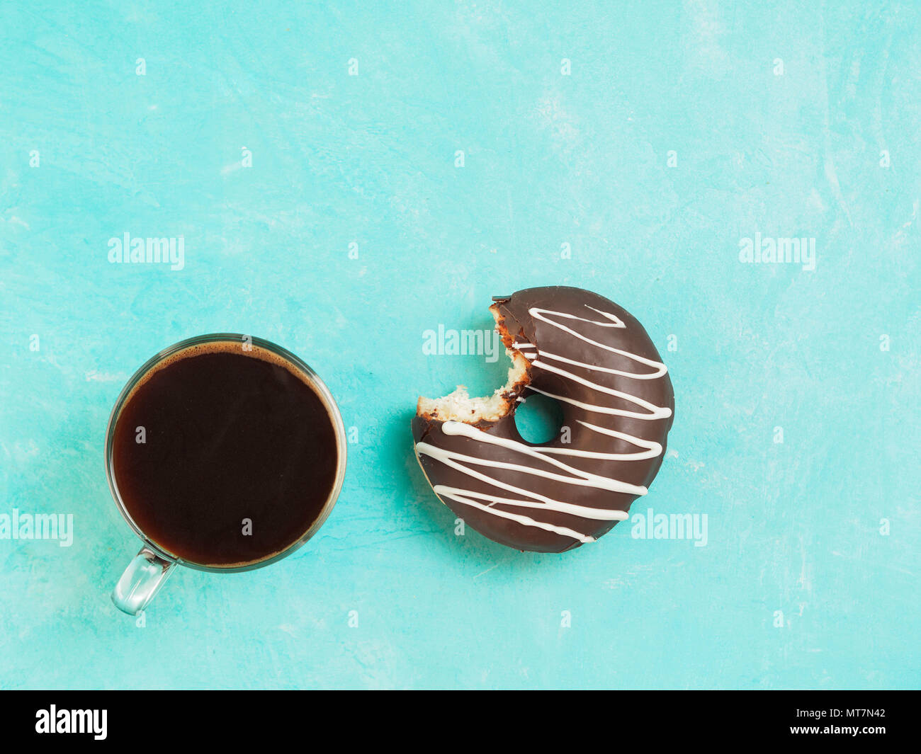Top view of chocolate donut and coffee on blue concrete background with ...