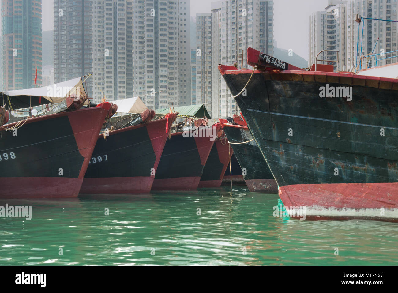 Commercial fishing boats lined up on Hong Kong harbour with apartments