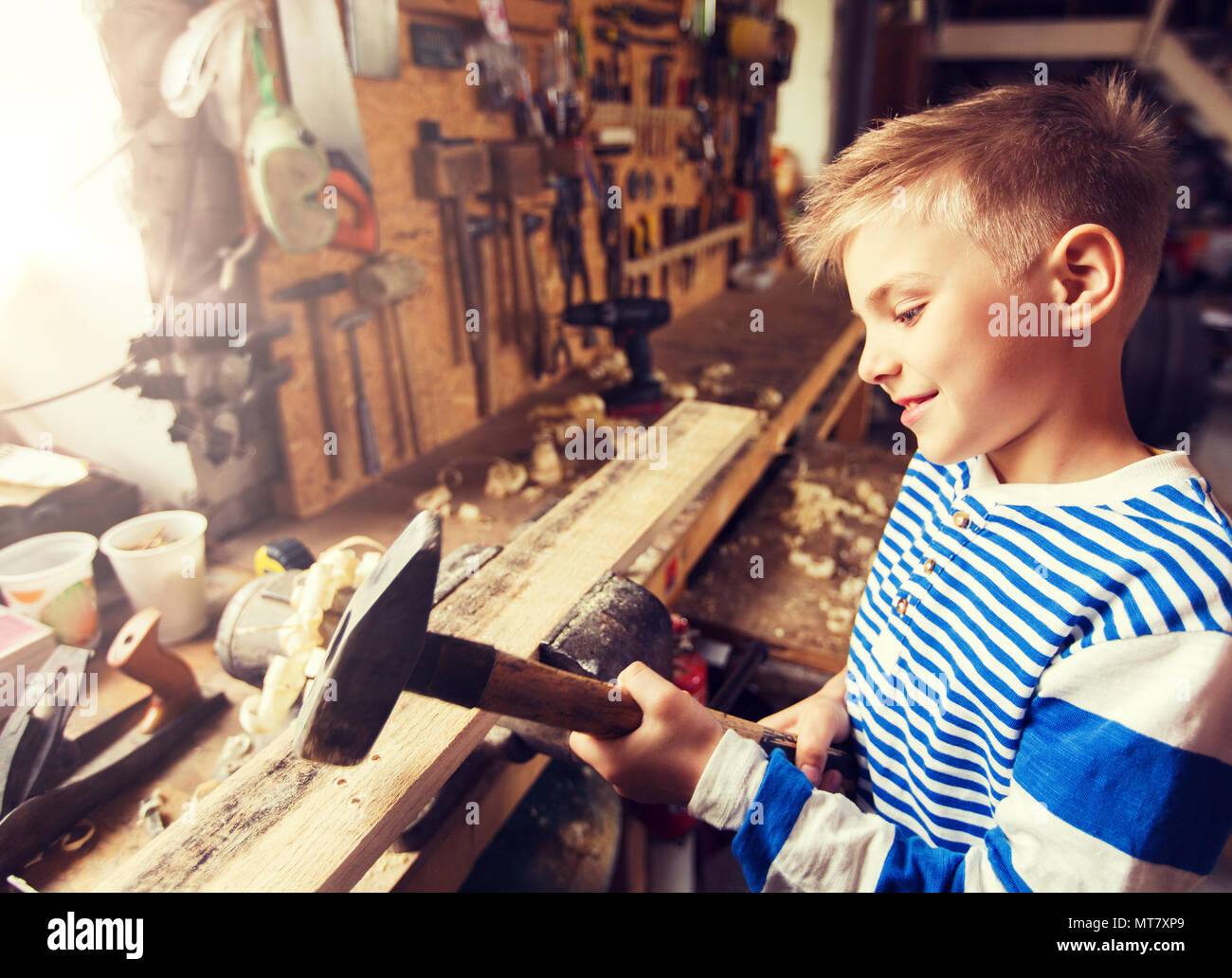 happy little boy with hammer and plank at workshop Stock Photo
