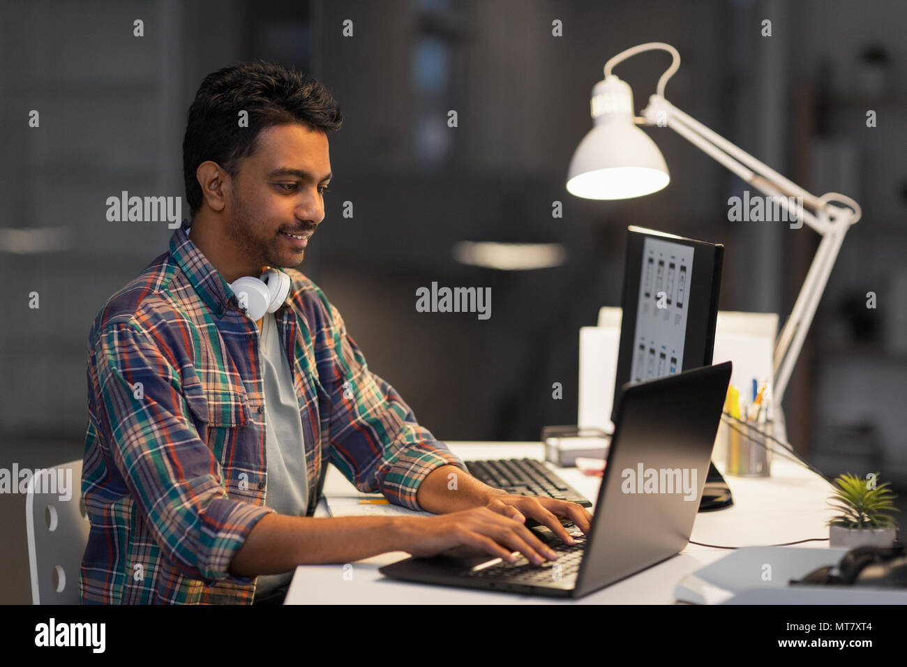 creative man with laptop working at night office Stock Photo - Alamy