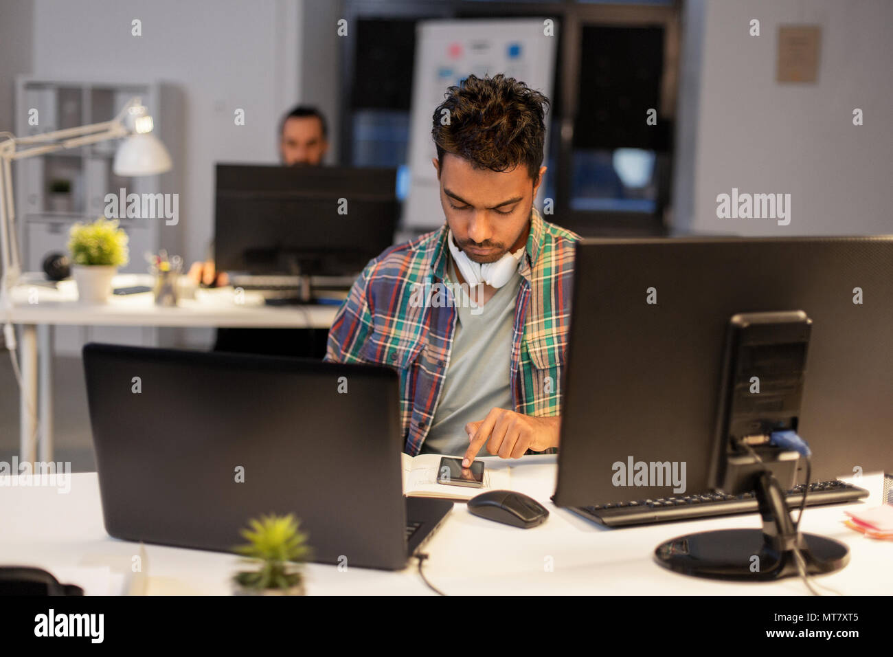 creative man with smartphone at night office Stock Photo