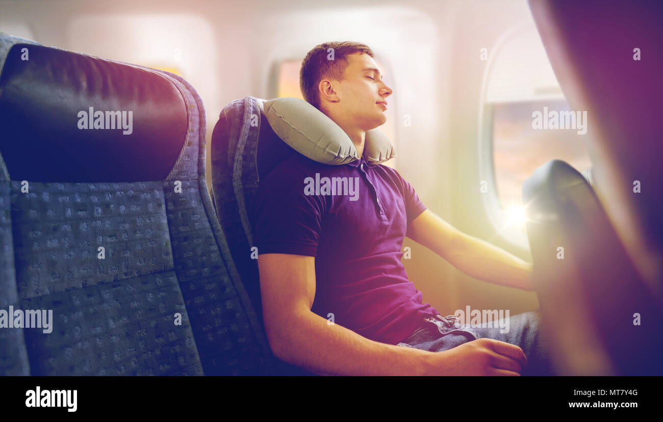 Young Man Sleeping In Plane With Travel Pillow Stock Photo