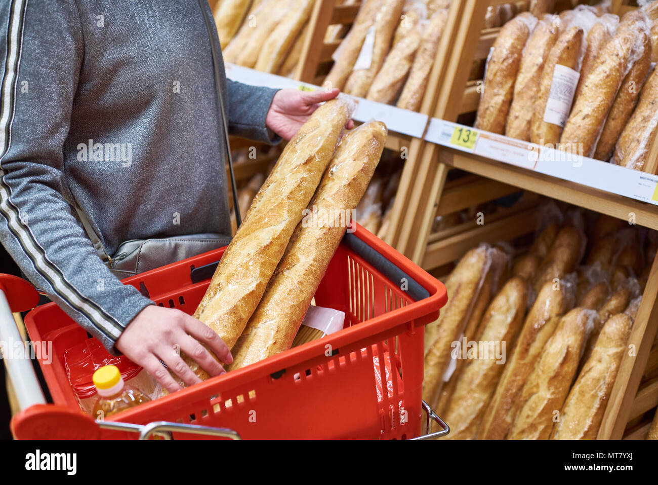Buyer with bread baguettes with a grocery basket in the store Stock Photo