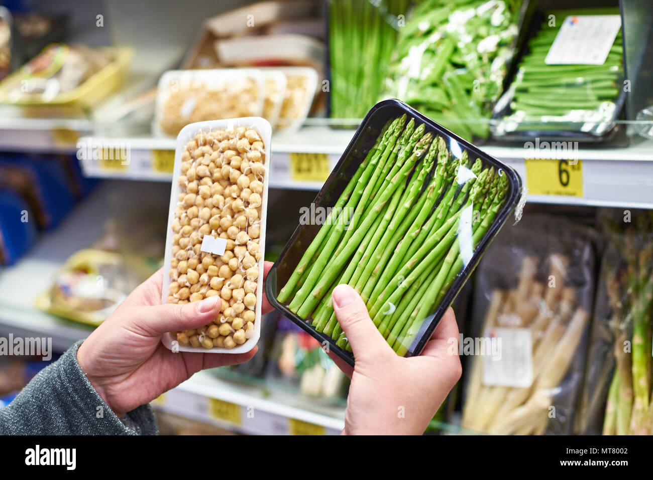Buyers hands with asparagus and sprouted peas in shop Stock Photo