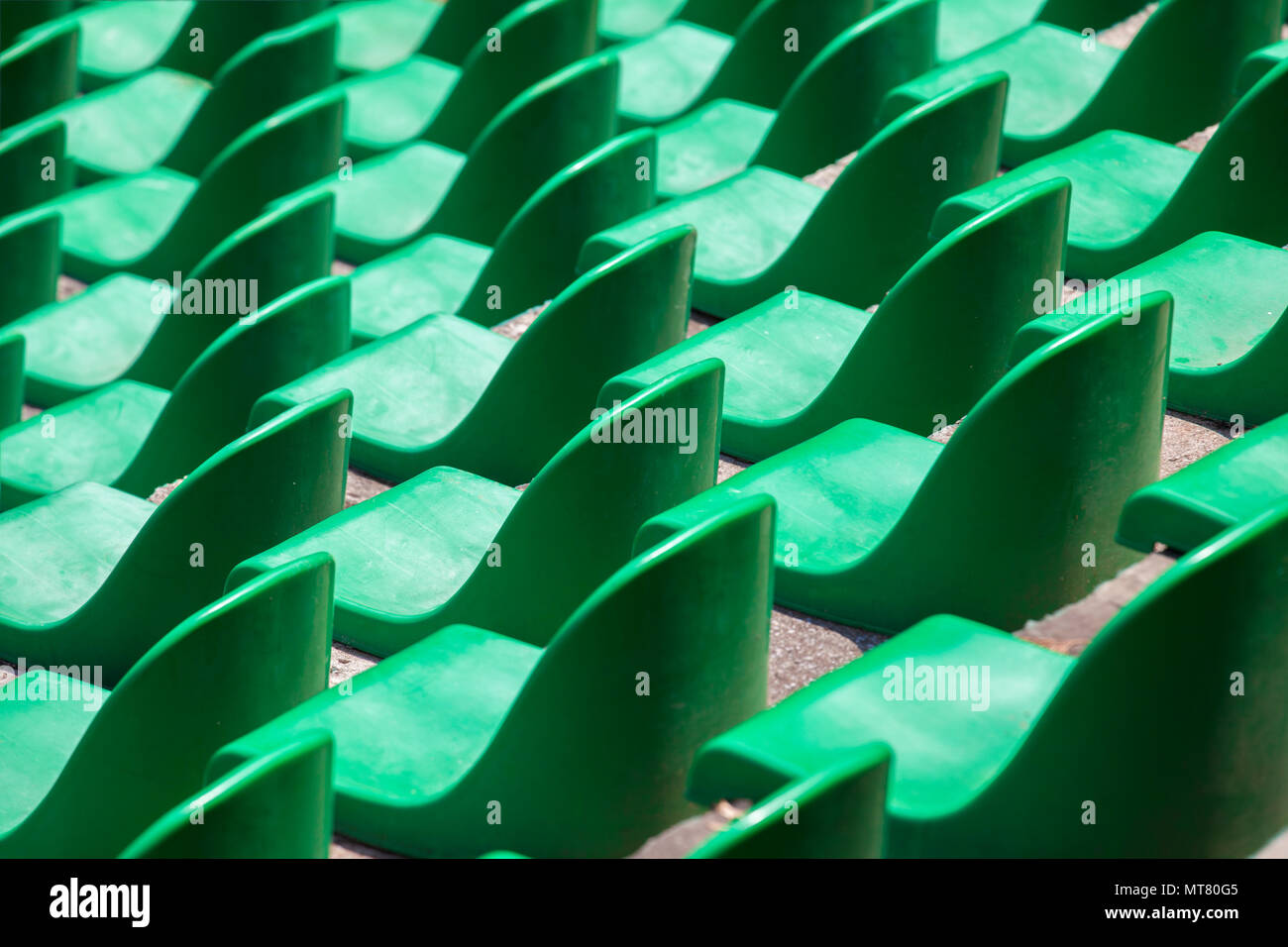Green plastic seats in rows in an empty stadium. Stock Photo