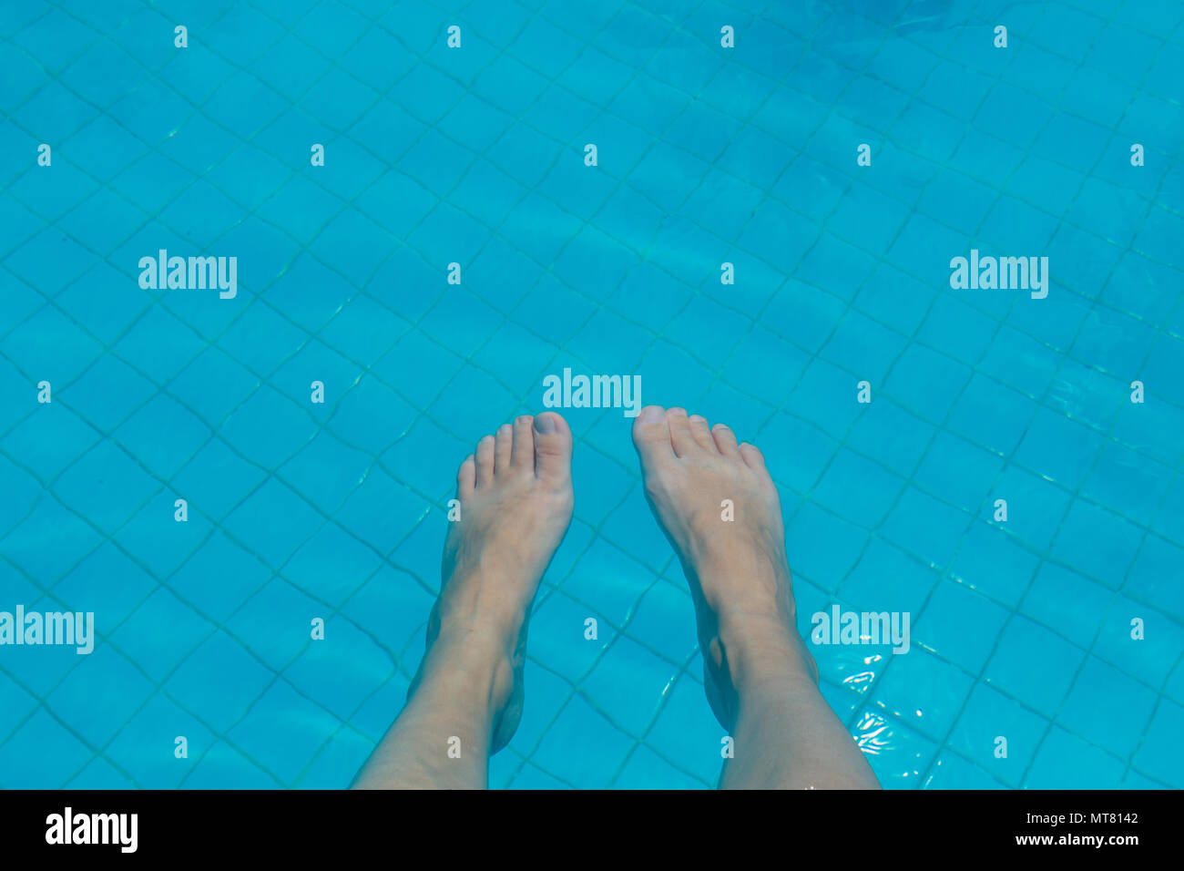 Bare Female Feet Under The Water Of A Swimming Pool Stock Photo