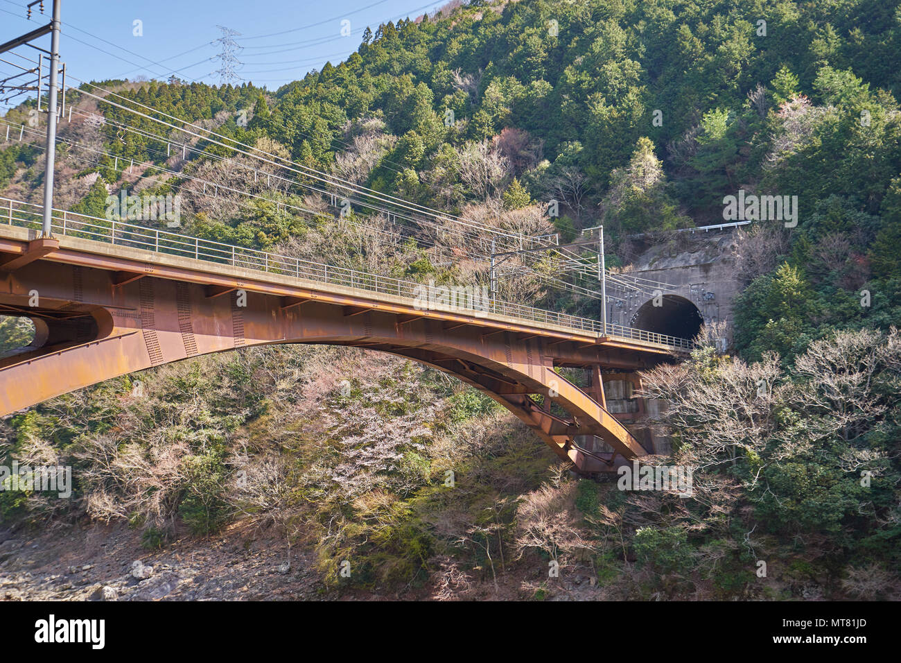 A raiilway bridge across the river into tunnel on mountain in Arashiyama, Kyoto, Japan. Stock Photo