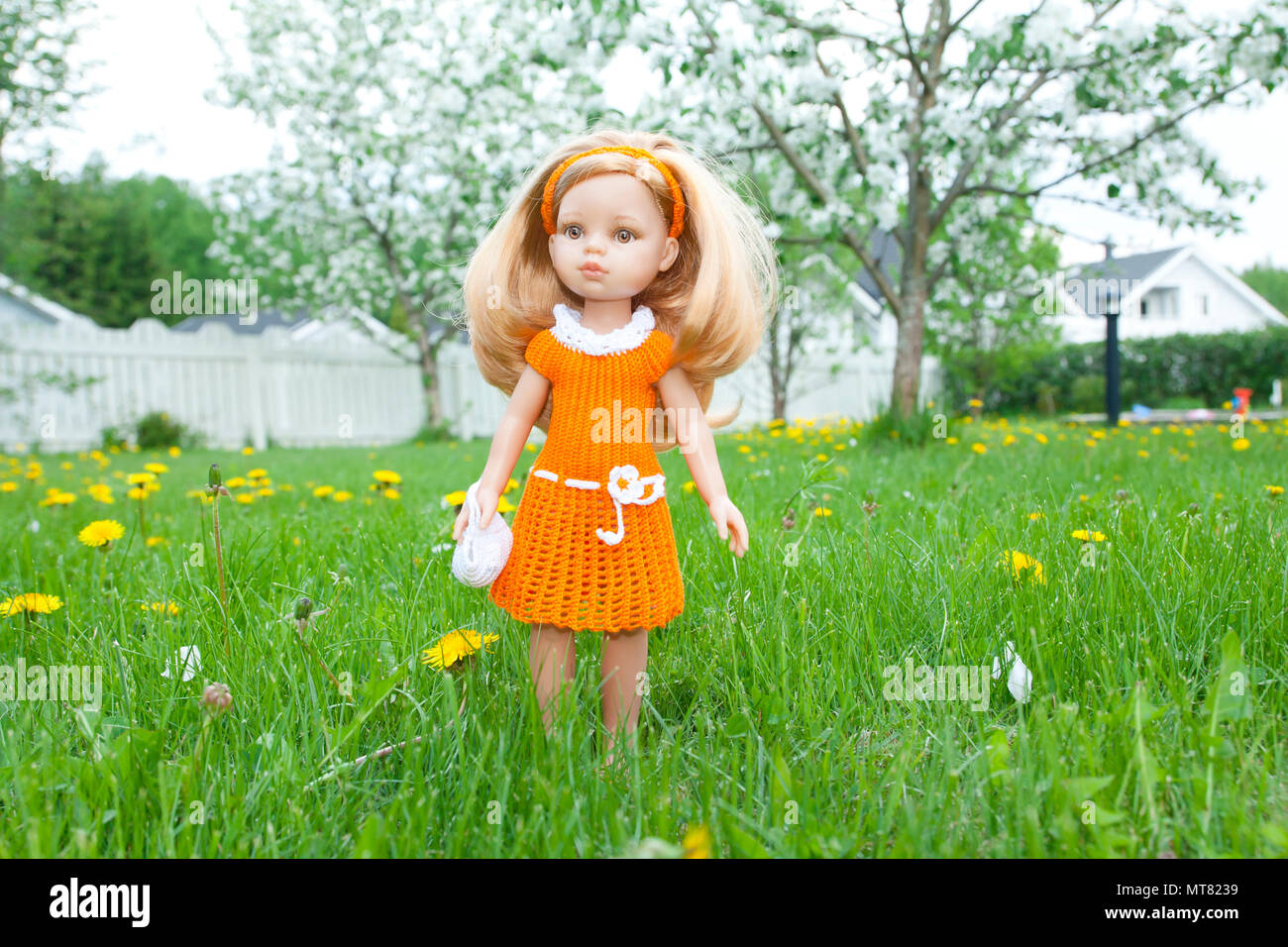 A beautiful doll with orange dress standing on green grass in the garden  Stock Photo - Alamy