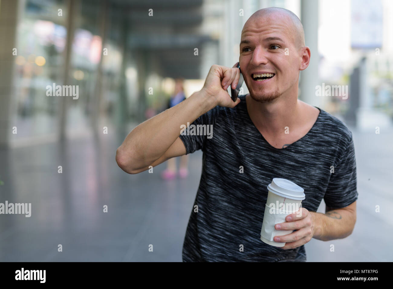 Thoughtful young happy bald man smiling and laughing while talki Stock Photo