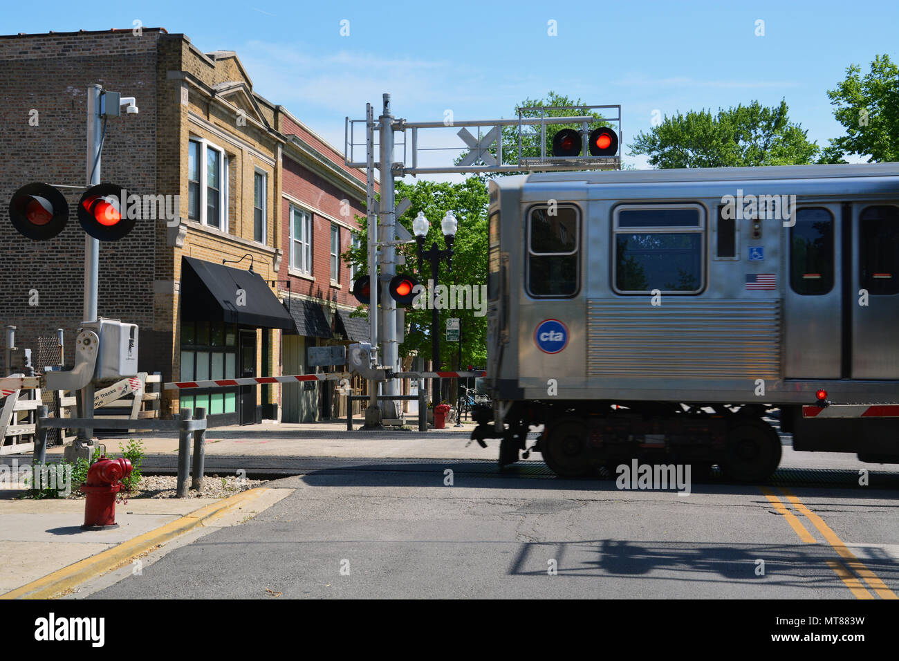 The brown line L-train crosses the Rockwell Ave. business district at street level in Chicago's Ravenswood Gardens neighborhood. Stock Photo