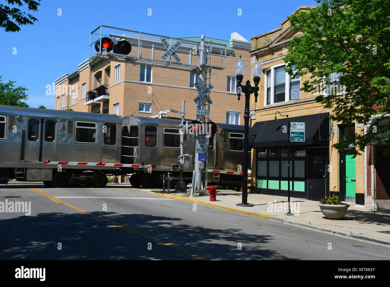 The brown line L-train crosses the Rockwell Ave. business district at street level in Chicago's Ravenswood Gardens neighborhood. Stock Photo
