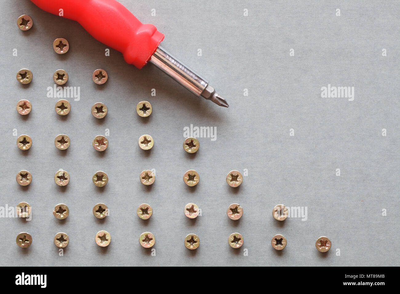 Background made from gray paper, screws and screwdriver Stock Photo