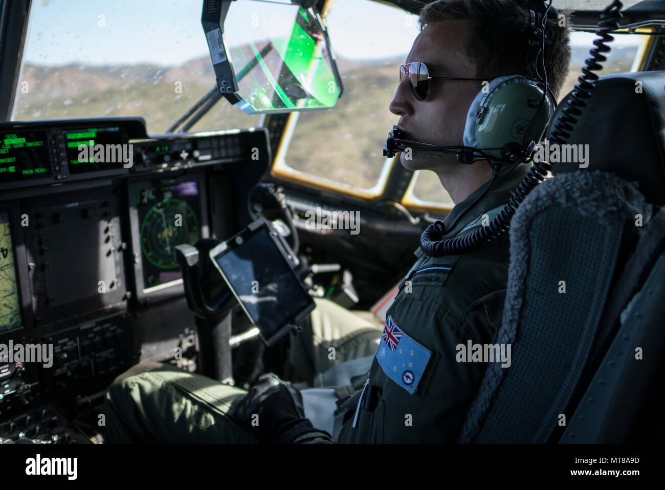 A No. 37 Squadron Royal Australian Air Force pilot looks out the window of a RAAF C-130J Hercules during a dissimilar formation flight with a U.S. Air Force 17th Special Operations Squadron MC-130J Commando II July 12, 2017 over Queensland, Australia. Talisman Saber 2017 provided the opportunity at further developing interoperability with counterparts from the RAAF through daily airborne operations to include low-level formation work, forward air refueling point, and personnel and cargo airdrops. (U.S. Air Force photo by Capt. Jessica Tait) Stock Photo