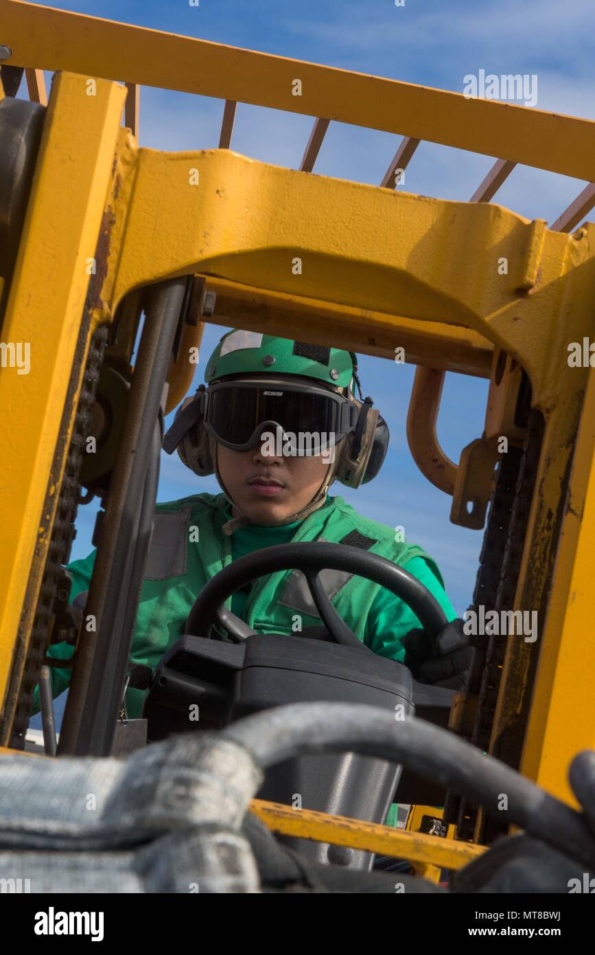 170715-N-OY799-376 CORAL SEA (July 15, 2017)   Logistics Specialist 3rd Class Erik Alagar drives a forklift with cargo on the flight deck of the Navy's forward-deployed aircraft carrier, USS Ronald Reagan (CVN 76), as part of a replenishment-at-sea during Talisman Saber 2017. Talisman Saber is a realistic and challenging exercise that brings service members closer and improves both U.S. and Australia's ability to work bilaterally and multilaterally, and prepares them to be poised to provide security regionally and globally. (U.S. Navy photo by Mass Communication Specialist 2nd Class Kenneth Ab Stock Photo