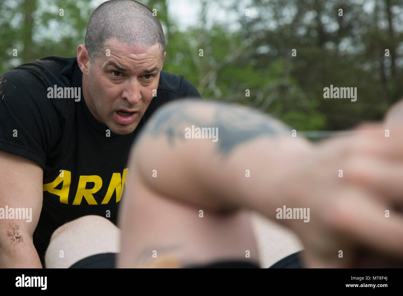 U.S. Army Staff Sgt. Mikki Sprenkle, a Combat Documentation/ Production Specialist, assigned to the 55th Signal Company (Combat Camera), assist his partner in completing the sit-ups event which is part of the Hilda's Challenge that is design to test physical endurance during the 2017 5th Annual SPC Hilda I. Clayton Best Combat Camera (COMCAM) Competition at Fort George G. Meade, Md., April 17, 2017. Sprenkle is competing in the 2017 5th Annual Best COMCAM Competition where teams of two compete throughout a weeklong event that tests their physical, mental and technical capabilities. The Competi Stock Photo