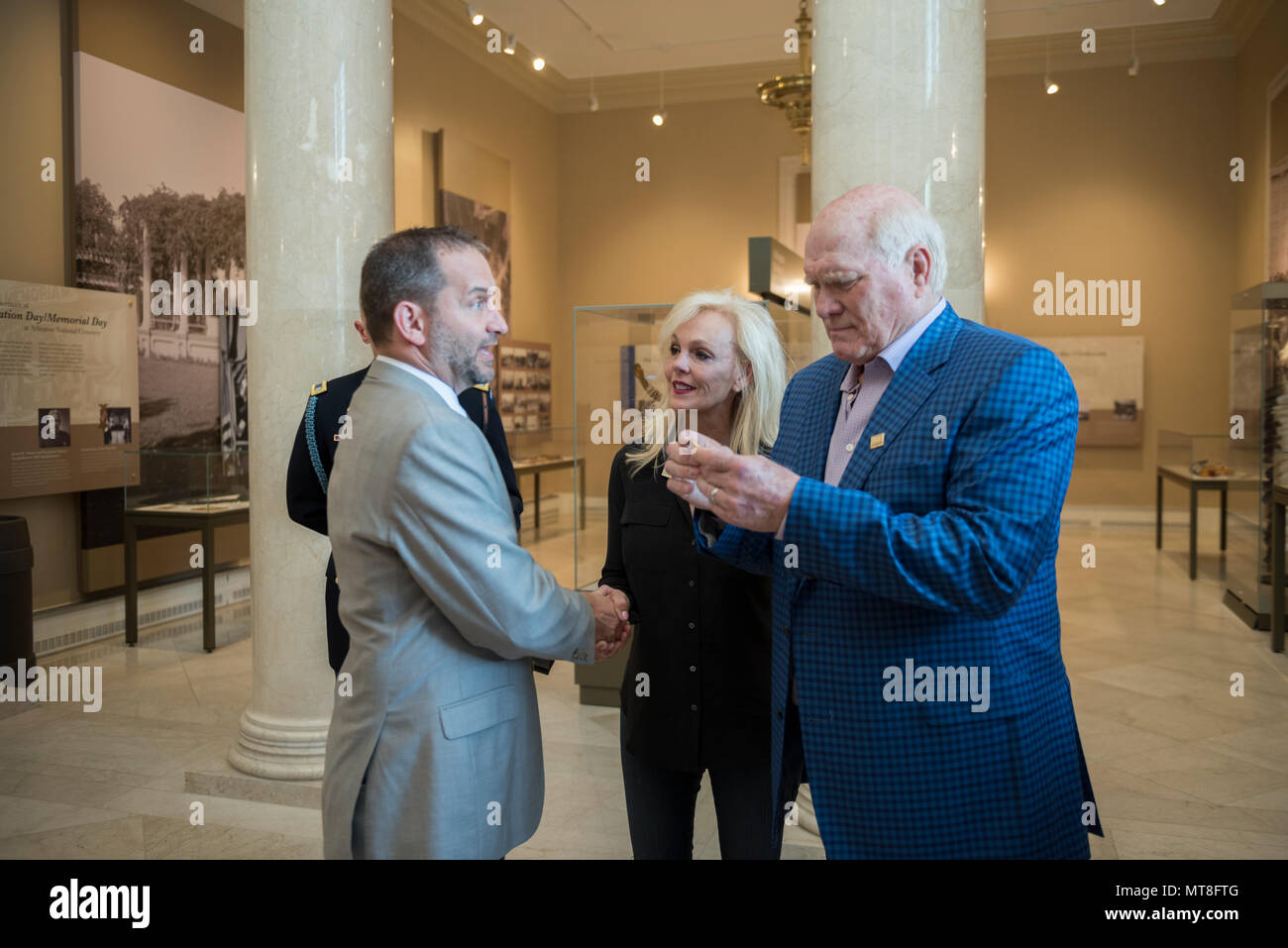 Micheal Migliara (left), director of events and ceremonies, Arlington National Cemetery; presents an Arlington National Cemetery coin to Terry Bradshaw (right), representative of United Service Organization (USO) Metro; and his wife, Tammy Bradshaw (center) in the Memorial Amphitheater Display Room at Arlington National Cemetery, Arlington, Virginia, May 11, 2018. Bradshaw participated in an Army Special Honors Wreath-Laying at the Tomb of the Unknown Soldier during his visit. (U.S. Army photo by Elizabeth Fraser / Arlington National Cemetery/ released) Stock Photo
