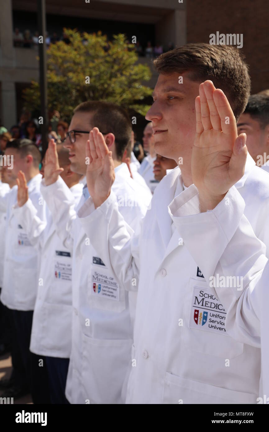 Navy Ensign Ryan Craig (right) recites the Hippocratic Oath as part of the annual White Coat ceremony at the Uniformed Services University of the Health Sciences, Bethesda, Md., May 11, 2018.  Craig was among the nearly 170 uniformed first-year medical students from USU's F. Edward Hebert School of Medicine -- 'America's Medical School' -- who received their traditional white coats, which symbolize the transition to clinical service and patient care. Stock Photo