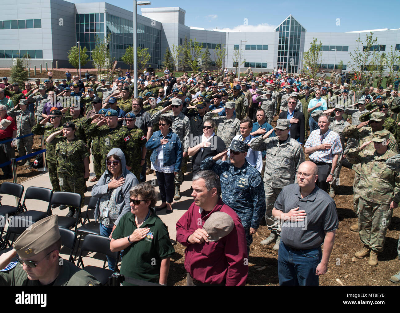 Members of the North American Aerospace Defense Command and U.S. Northern Command and invited guests salute during the singing of the Canadian and U.S. National Anthems during  the unveiling ceremony for a memorial cairn outside the NORAD and USNORTHCOM headquarters building on Peterson Air Force Base, Colorado, May 11. The cairn honors the Canadian service men and women who passed away while serving at NORAD in Colorado Springs. The placement and dedication of the cairn was conducted in conjunction with the 60th Anniversary of NORAD and the U.S. Canadian binational NORAD agreement. (DoD Photo Stock Photo