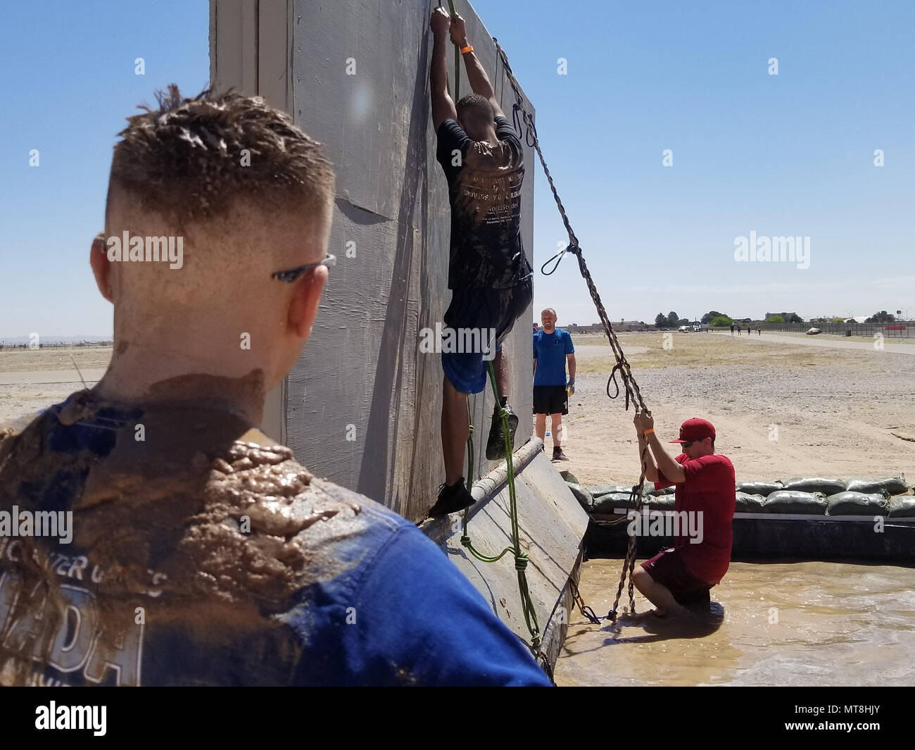 A competitor attempts to climb over a wall obstacle at the Old Ironsides Mud Challenge at Fort Bliss, Texas, May 12, 2018. The four-mile course is designed to promote physical fitness while also allowing the El Paso and surrounding communities to come together and have fun. (U.S. Army photos by Pfc. William Dickinson) Stock Photo