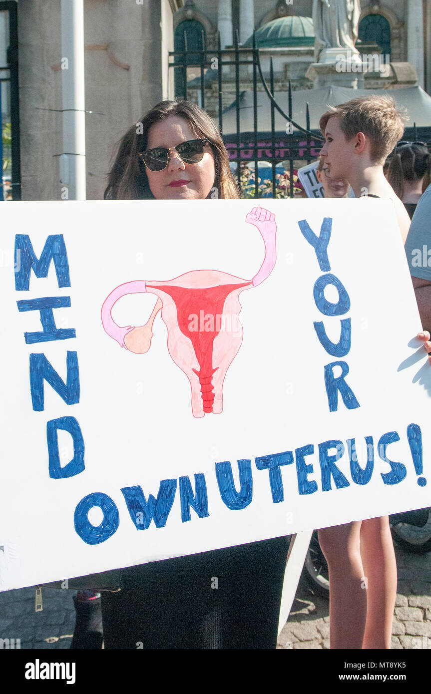 Belfast, Northern Ireland. 28/05/2018 - A woman holds a placard saying 'Mind your own uterus!'  Around 500 people gather at Belfast City Hall to call for the decriminalisation of abortion in Northern Ireland.  It comes the day after a referendum held in the Republic of Ireland returned a substantial 'Yes' to removing the 8th amendment to the constitution, which gives equal right of life to both the mother and baby, effectively banning abortion in all circumstances. Stock Photo