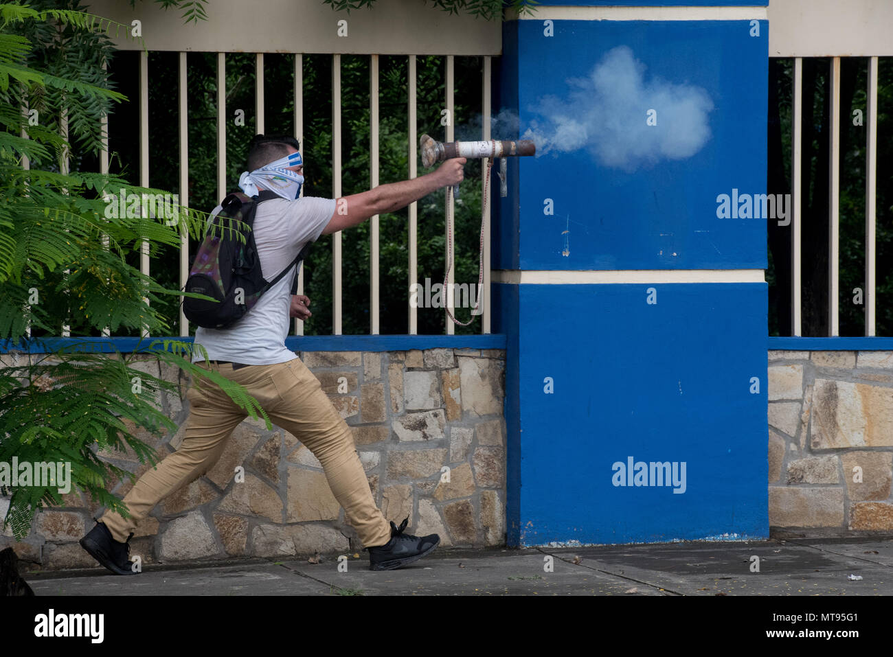 28 May 2018, Nicaragua, Managua: A hooded man shoots with an improvised weapon during protests surrounding the capture of the University of Engineering. Students had barricaded themselves in the university and demanded the independence of the educational establishment from the state. The clashes resulted in clashes between the students, security forces and an unidentified group. Photo: Carlos Herrera/dpa Stock Photo