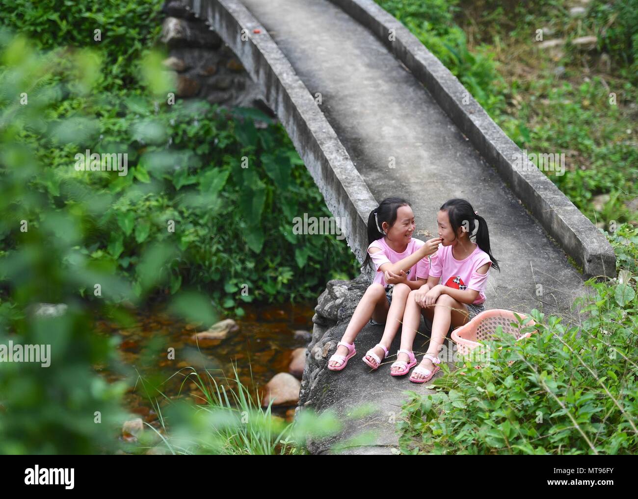 Nanchang, China's Jiangxi Province. 23rd May, 2018. Eleven-year-old Pan Xuejing (L) and her twin sister Pan Xueying take a rest in Suolong Village of Yudu County, east China's Jiangxi Province, May 23, 2018. With about 1,000 residents, Suolong Village has 29 cases of multiple births, a high rate considering the modest population size. Credit: Hu Chenhuan/Xinhua/Alamy Live News Stock Photo