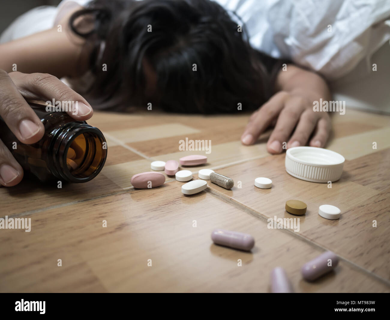 Woman lying on the floor after an overdose of pills at home.  Overdose and suicide concept. Stock Photo