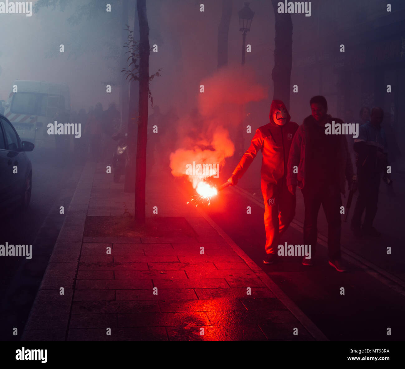Protestors wearing a Guy Fawkes mask light gas canisters to express