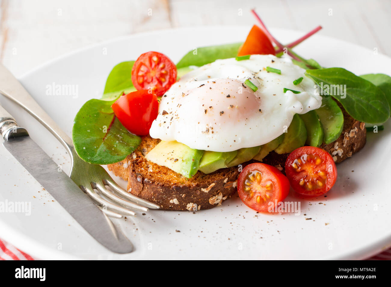 Healthy whole grain bread toast with avocado, poached egg, cherry