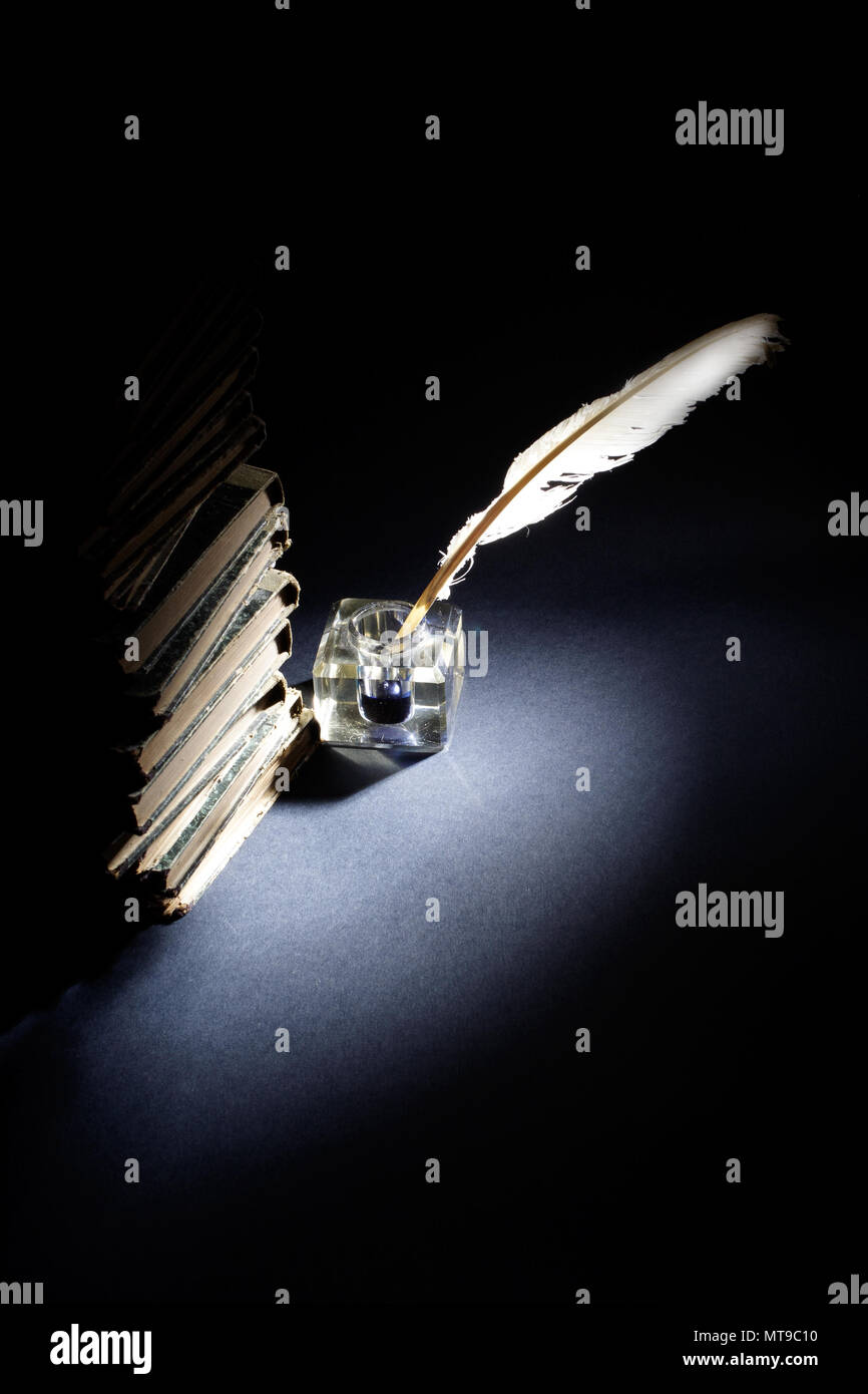 Old fountain pen, books and inkwell on a black background Stock Photo