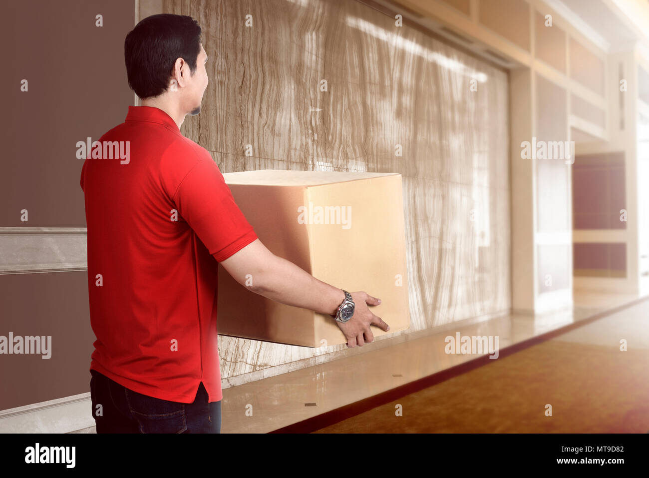 Attractive asian delivery man holding the package to delivered Stock