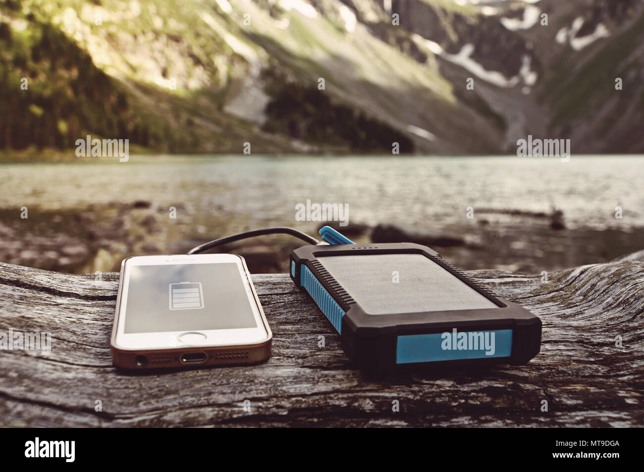 battery pack with solar battery charges the smartphone in the wild on a background of mountains and rivers Stock Photo