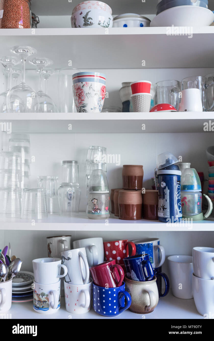 Kitchen cupboard with stacks of mugs and cups. Stock Photo