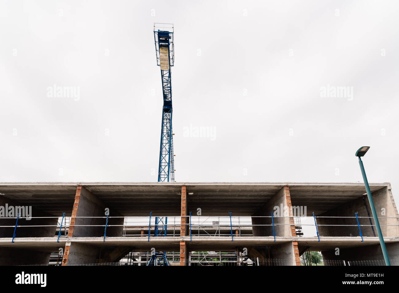 Low angle view of construction crane against building and cloudy sky. Stock Photo