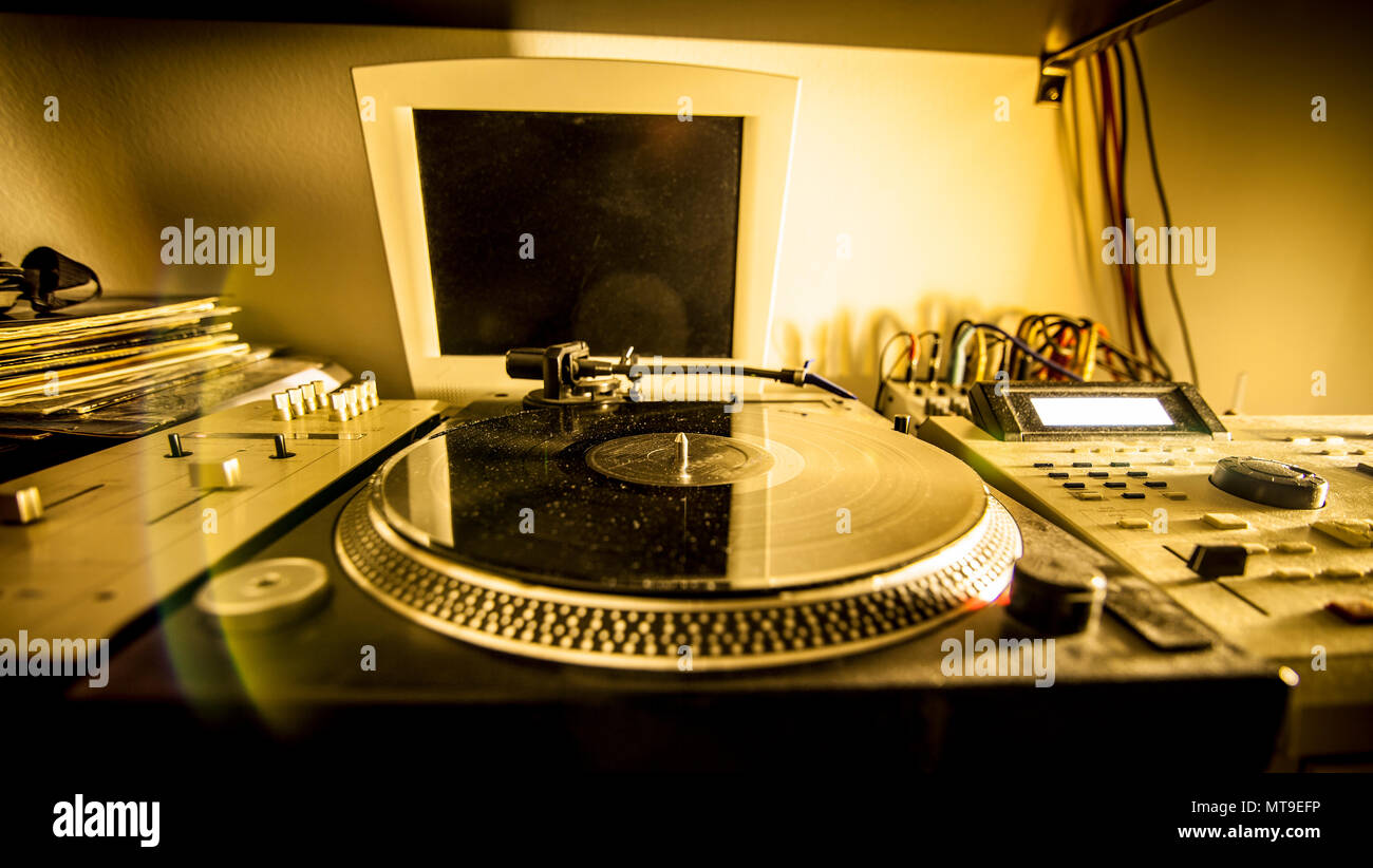 Turntable in home recording studio illuminated by a yellow light Stock Photo