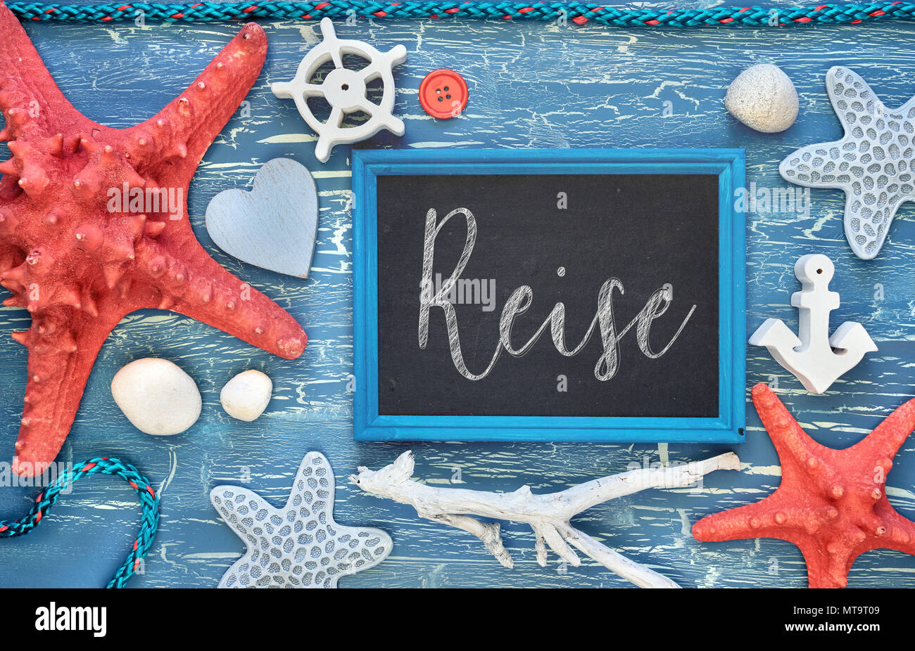 Blackboard With Maritime Decorations on cracked blue wood, text in German. 'Reise' means 'Vacations'. Stock Photo