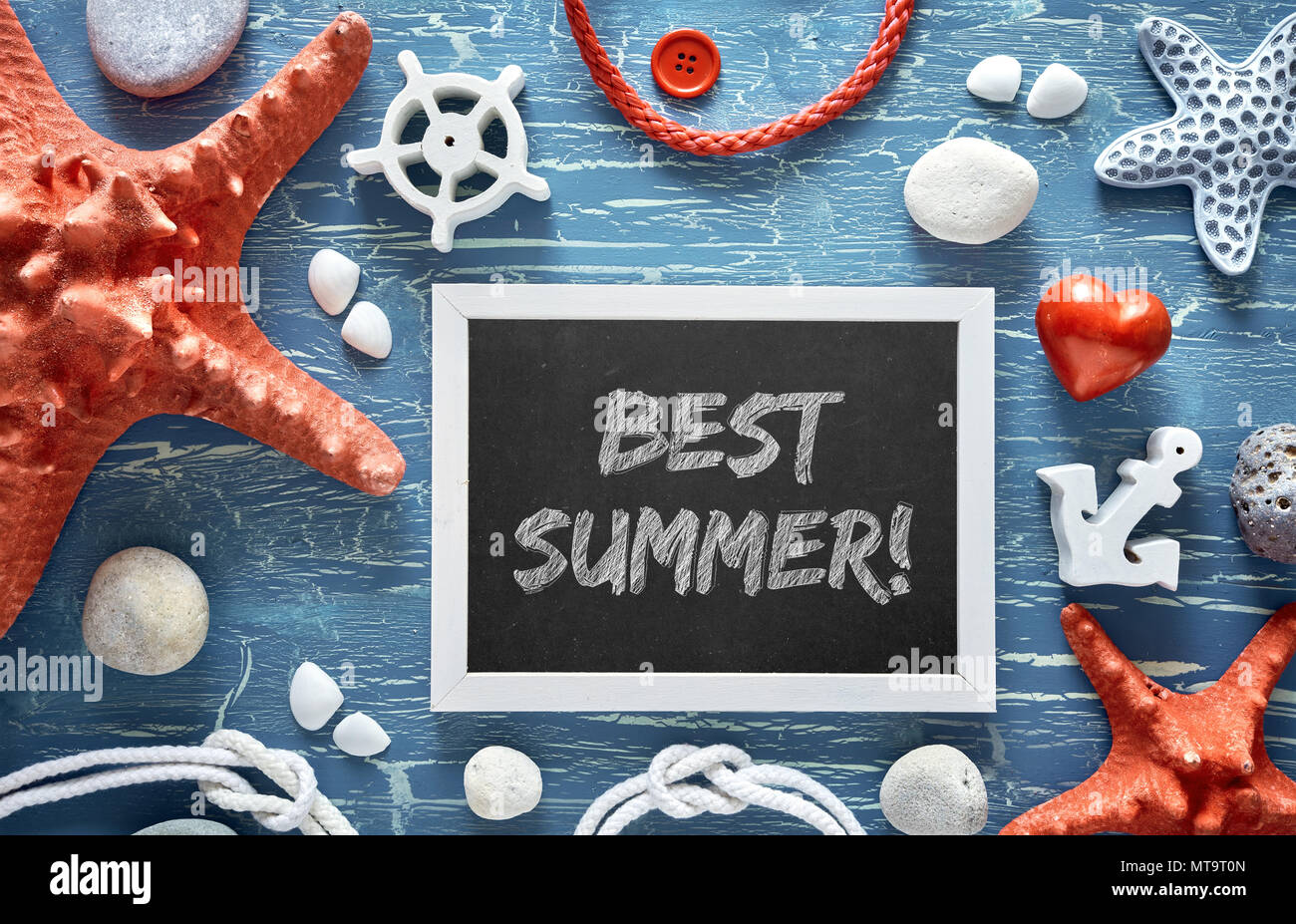 Blank blackboard with sea shells, stones, rope and star fish on blue wooden background, text 'Best Summer' Stock Photo