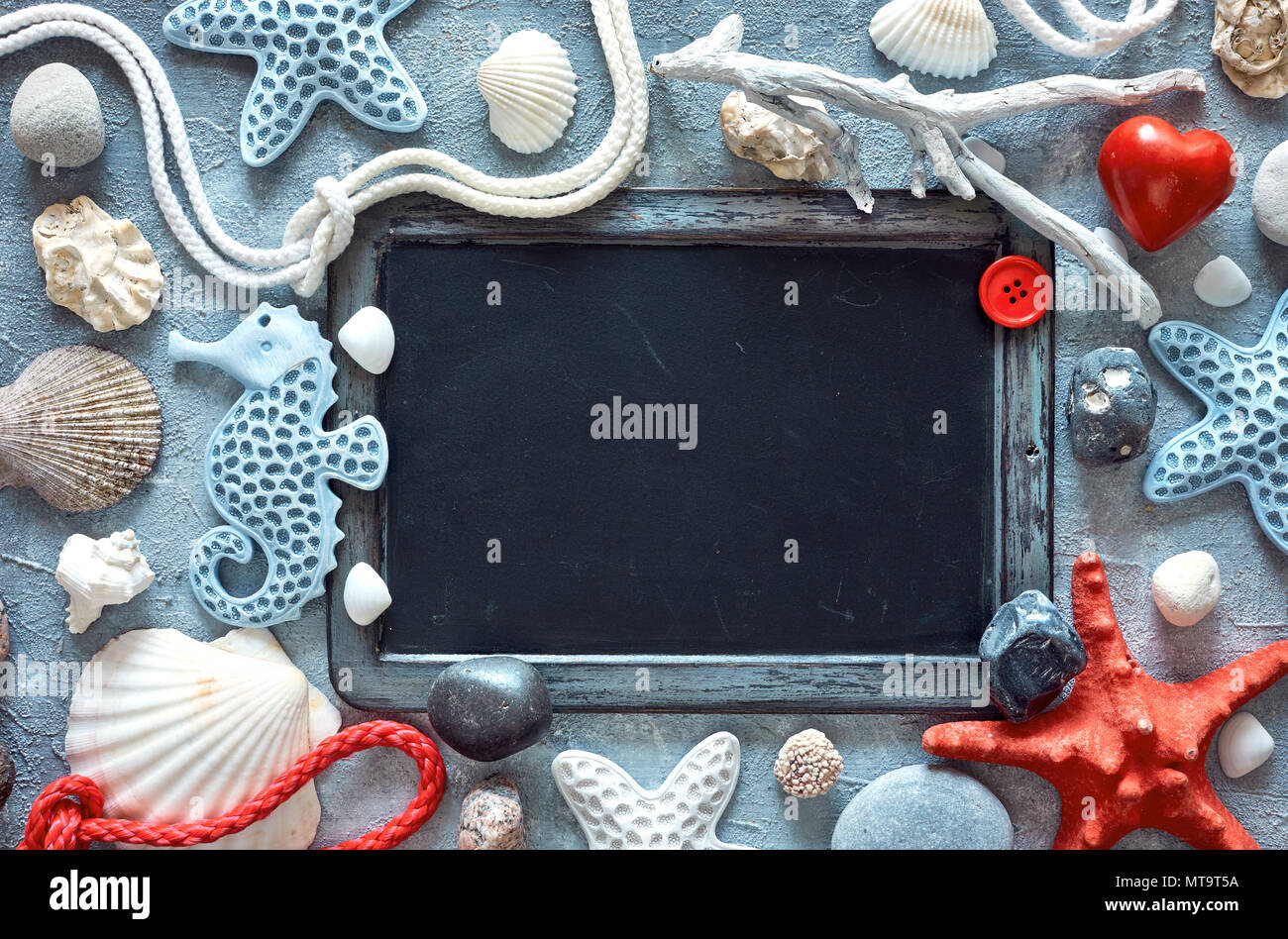 Blank blackboard with sea shells, stones, rope and star fish on textured light blue background, text space Stock Photo