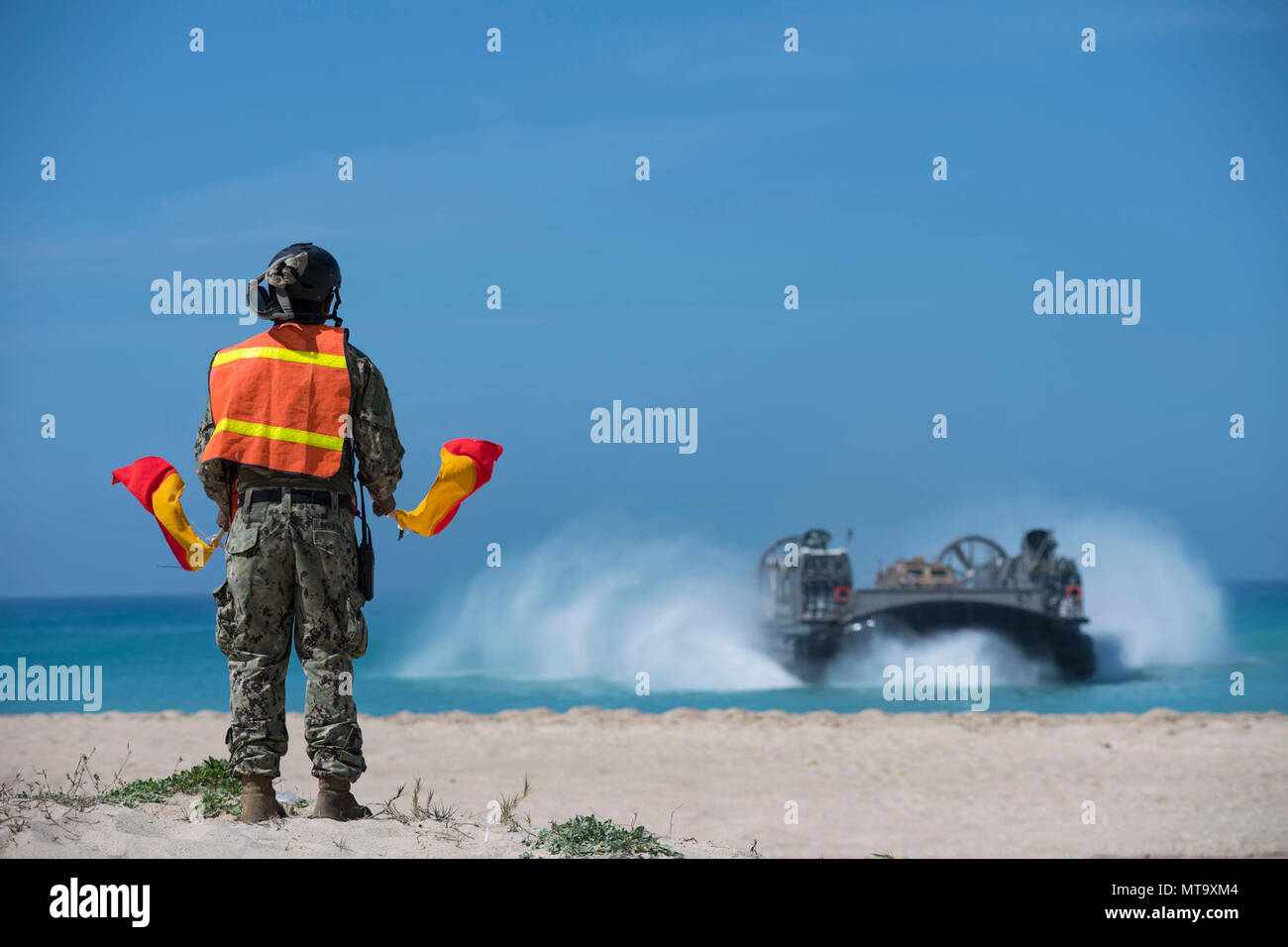HAIFA, ISRAEL (March 7, 2018) Logistics Specialist Seaman Denny Figueroa, from Bayamon, Puerto Rico, and assigned to Beach Master Unit (BMU) 2, signals Landing Craft, Air Cushion 67, attached to Assault Craft Unit (ACU) 4, as it prepares to make landfall on the beach in Israel, March 7, 2018. The Wasp-class amphibious assault ship USS Iwo Jima (LHD 7), homeported in Mayport, Florida, is participating in Juniper Cobra 2018 and conducting naval operations in the U.S 6th Fleet area of operations. JC18 is a computer-assisted exercise conducted through computer simulations focused on improving comb Stock Photo