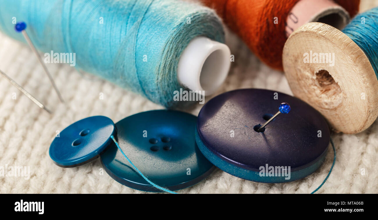 colored thread and buttons on white knitted fabric Stock Photo - Alamy