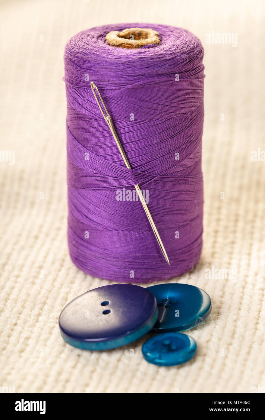 colored thread and buttons on white knitted fabric Stock Photo - Alamy